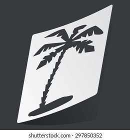 White sticker with black image of palm on beach, on black background