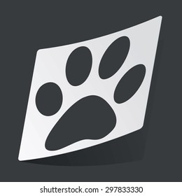 White sticker with black image of paw print, on black background