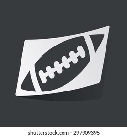 White sticker with black image of rugby ball, on black background