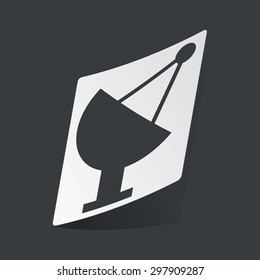 White sticker with black image of satellite dish, on black background