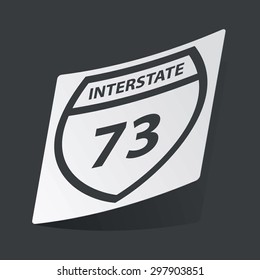 White sticker with black image of shield with text Interstate 73, on black background