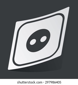 White sticker with black image of socket, on black background
