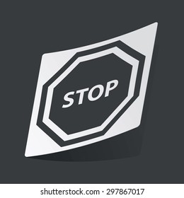White sticker with black image of STOP sign, on black background