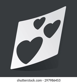 White sticker with black image of three hearts, on black background