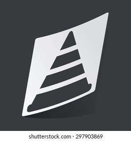 White sticker with black image of traffic cone, on black background