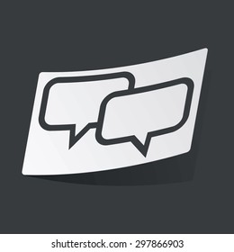 White sticker with black image of two chat bubbles, on black background
