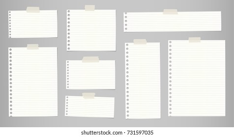 White striped note, notebook paper for message or text stuck with sticky tape on gray background.