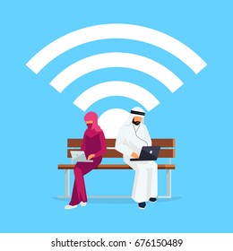 Wi-Fi concept. Young Muslim couple in a flat style of sitting on the bench. Arab men and women in traditional clothes read using a tablet pc. Vector illustration.