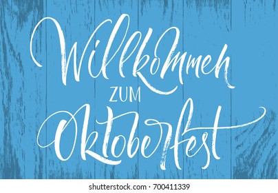 Willkommen zum Oktoberfest (German) / Welcome to Oktoberfest (English) lettering on blue wood background. Handwritten modern calligraphy, brush painted letters. Vector illustration. 