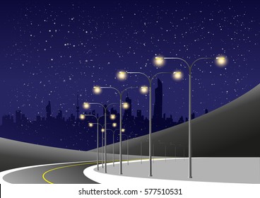 Winding Night Road Lit By Electrical Light Poles And City Skyline