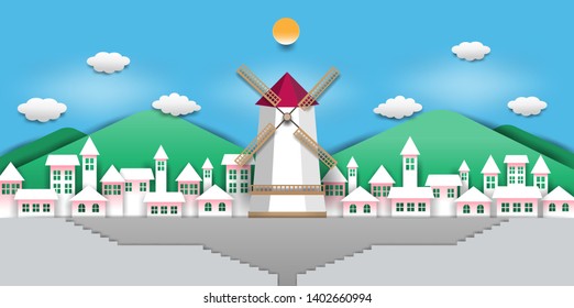 Windmill is located in the center of the white village On a blue background with clouds and mountains, paper art design.