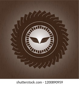 wings icon inside badge with wood background