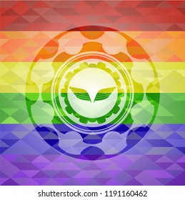 wings icon inside emblem on mosaic background with the colors of the LGBT flag