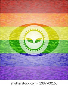 wings icon inside emblem on mosaic background with the colors of the LGBT flag