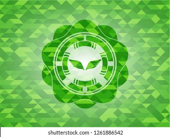 wings icon inside green emblem with triangle mosaic background