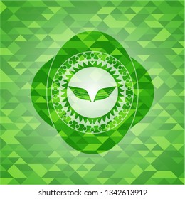 wings icon inside green emblem with triangle mosaic background