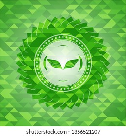 wings icon inside green emblem with mosaic ecological style background