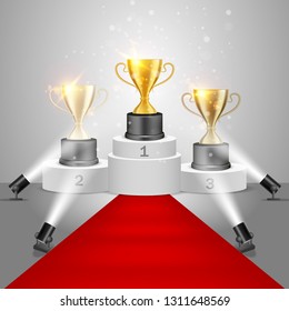 Winner awards on victory pedestal, vector realistic illustration. Gold, silver and bronze trophy cups on white podium with red carpet illuminated by floor spotlights.