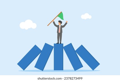 Winner takes all concept. Business competition leaves only the strongest. Strength to survive in business crisis. A businessman standing between upright domino among falling dominoes
