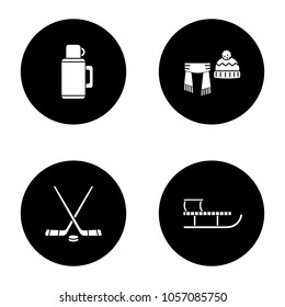 Winter activities glyph icons set. Thermos, scarf and hat, ice hockey sticks and puck, sled. Vector white silhouettes illustrations in black circles