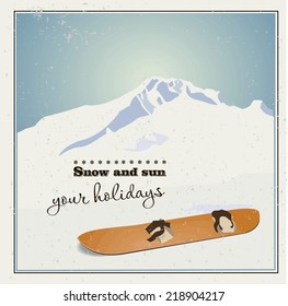 Winter  background. Mountains and old snowboard in the snow