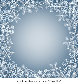 Winter frame made of fluffy snowflakes on soft blue background with space for text.