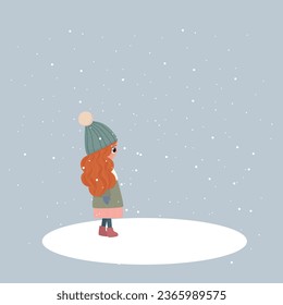 Winter picture. A girl with red hair stands under the snowfall