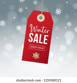 Winter sale poster template. Hanging red gift tag, label with gingerbread cookie, falling snowflakes bokeh lights and blurred background. Modern vector illustration. Business concept.