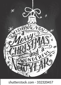 Wishing you a Merry Christmas and a wonderful New Year. Hand lettered quote inside a Christmas ball on blackboard background with chalk