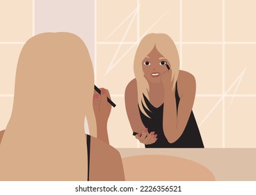 Woman applying makeup in the bathroom. Beautiful tanned blonde girl is reflected in the mirror and applies make up. Young woman standing in front of a mirror. Girl draws arrows on her eyes