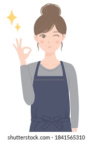 A woman in an apron doing an OK pose