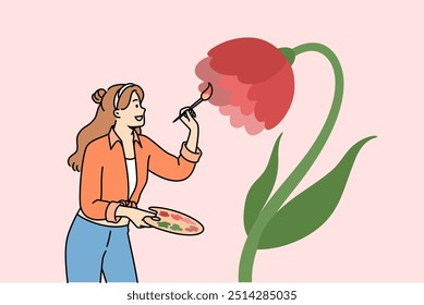 Woman artist paints flower on wall to decorate interior, uses wooden palette and brush. Positive girl artist enjoys drawing and opportunity to develop creativity and professional skills