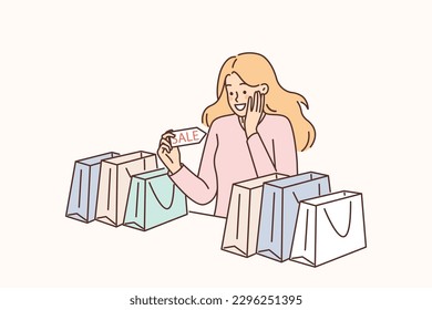 Woman with bags from fashion store holds flyer with inscription sale and rejoices at opportunity of shopping. Attractive girl enjoys shopping on black friday with good discounts or cashback 