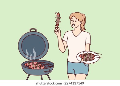 Woman barbecues on outdoor grill in backyard of home preparing for picnic party. Girl fries barbecues meat and BBQ vegetables on hot coals, wanting to get delicious snack with smell of smoke 