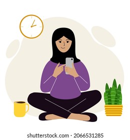 A woman in a black headscarf is sitting cross-legged and working on a mobile. Remote work or communication over the Internet. Vector flat illustration.