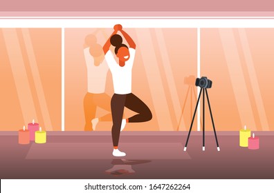 woman blogger doing yoga exercises sportswoman recording online video with camera on tripod healthy lifestyle live streaming blogging concept modern gym interior horizontal full length vector