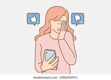 Woman blogger suffers sees dislikes under own post on social network and cries holding phone in hand. Frustrated girl feels unhappiness and despair due to dislikes or internet bullying