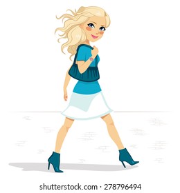 Woman in blue outfit and high heel boots walking street with blue purse on shoulder