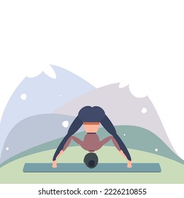 A woman in blue-brown clothes is doing yoga in a standing pose with her legs wide apart and her torso down. Outside near the mountains.