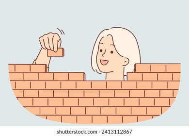 Una mujer construye una pared de ladrillo con bloques cuidadosamente apilados, para el concepto de crear estructuras de negocios. Chica feliz construye valla para protegerse de la influencia de gente desagradable o de la información dañina