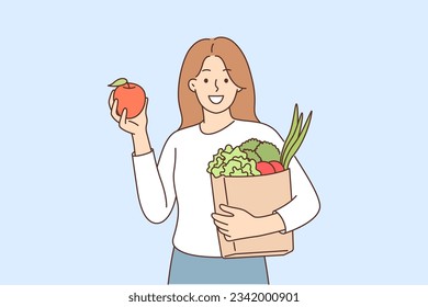 Woman buyer bought fruits and vegetables in grocery supermarket and holds paper bag recommending to refuse plastic packaging. Girl buyer of organic food store smiles and looks at screen