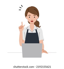 a woman in cafe apron using laptop computer getting ideas with pointing hand gesture at her desk