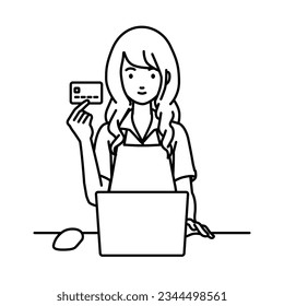 a woman in cafe apron using laptop computer at her desk and holding a credit card