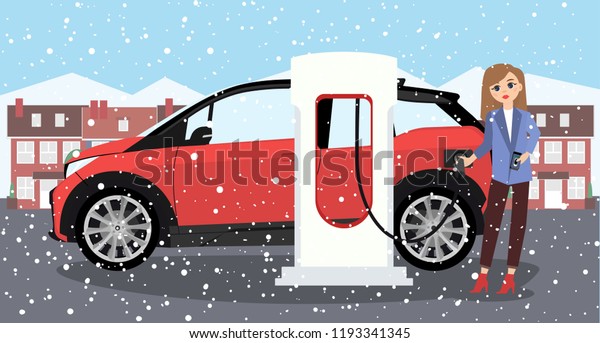 Woman charges an electric\
car at a charging station for electric vehicles. Winter time.\
Snow.
