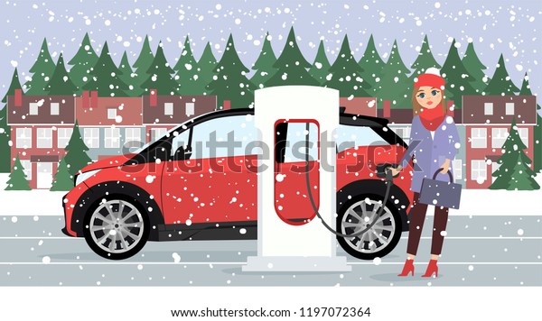 Woman charges an electric\
car at a charging station for electric vehicles. Winter time.\
Snow.