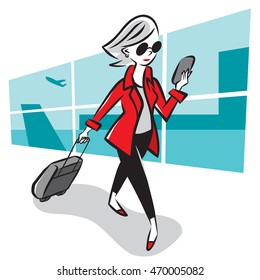 A woman checks her smartphone as she walks through an airport terminal.