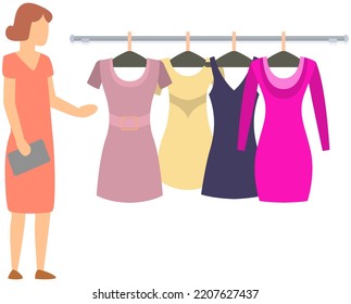 Woman choose dress hanging on hangers. Girl shopper going to try on new clothes. Shopping lady in clothing store mall, buyer in shop. Person looks at attire, chooses clothing products in store