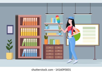 woman cleaner in uniform holding dust brush female janitor dusting bookshelves professional cleaning service concept creative co-working center modern office interior full length flat horizontal