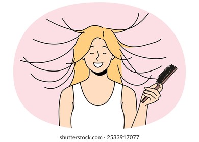 A mulher penteia o cabelo e sorri, vendo o efeito da magnetização estática do penteado. Engraçado jovem loira menina toma conta do próprio cabelo se preparando para o encontro e rindo sentimento surto de emoções positivas