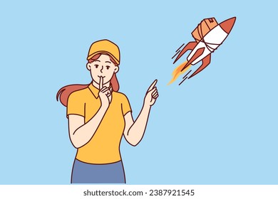 Woman courier near rocket with package puts finger to mouth offering express delivery services. Girl from courier service promises to quickly deliver goods thanks to well-functioning logistics chains